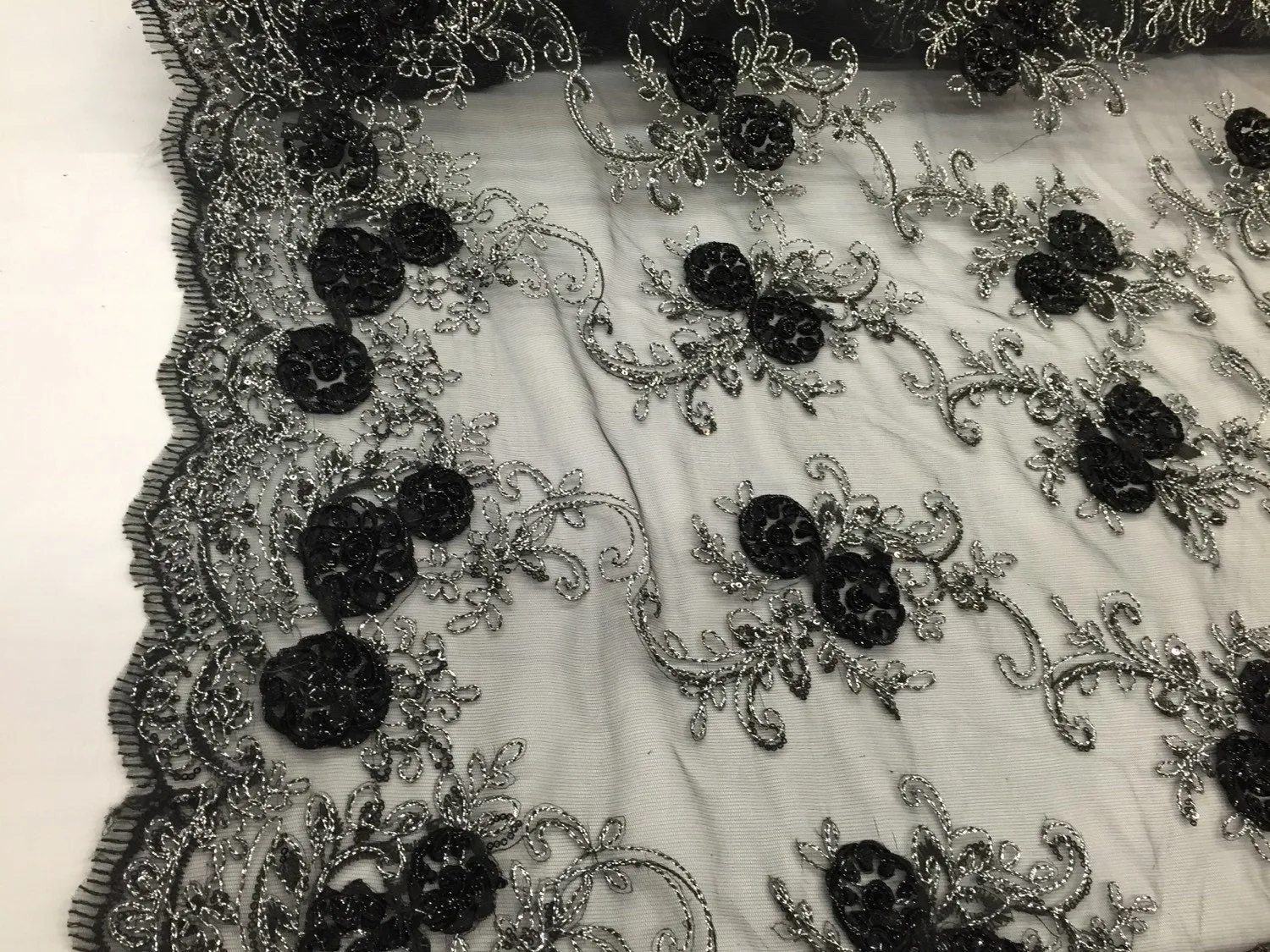 Black/silver  3d flowers embroider with sequins on a mesh lace fabric. Sold by the yard.